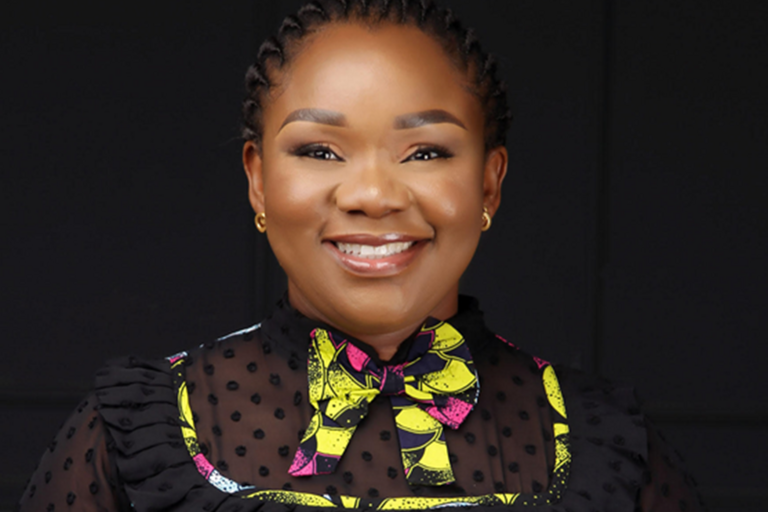 Young woman smiling wearing a black, yellow, white and pink African fabric dress