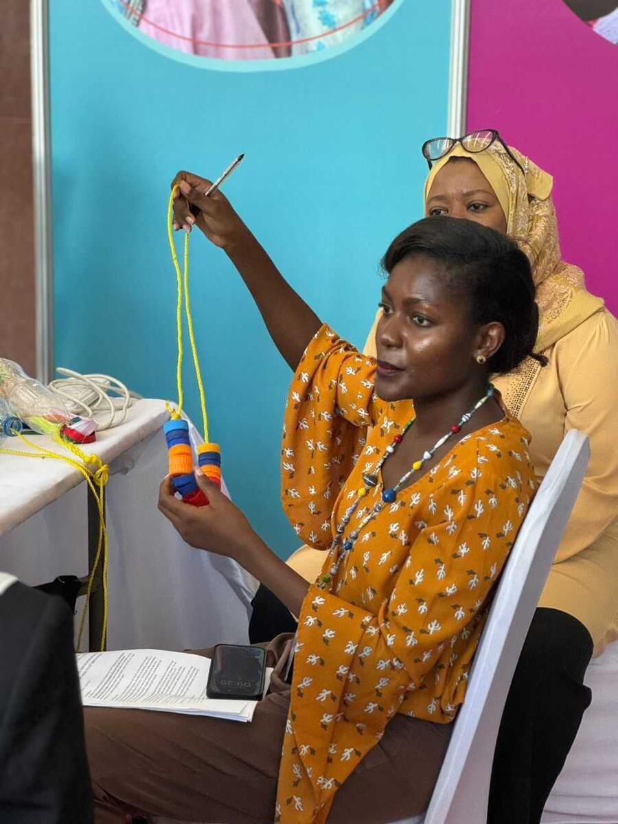 Gloria demonstrates Tanzanian-made children's play materials at the  2024 East Africa Regional Early Childhood Conference.